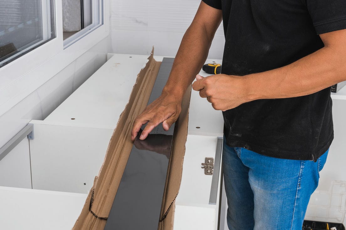 man installing countertop on the cabinets in kitchen - Milwaukee kitchen renovation and remodeling
